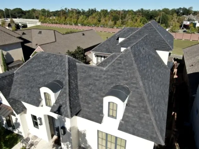 Charcoal shingle roof and arched dormer windows on a white two-storey home.