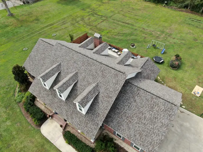 Aerial view of a brick home with three dormers and a new roof.